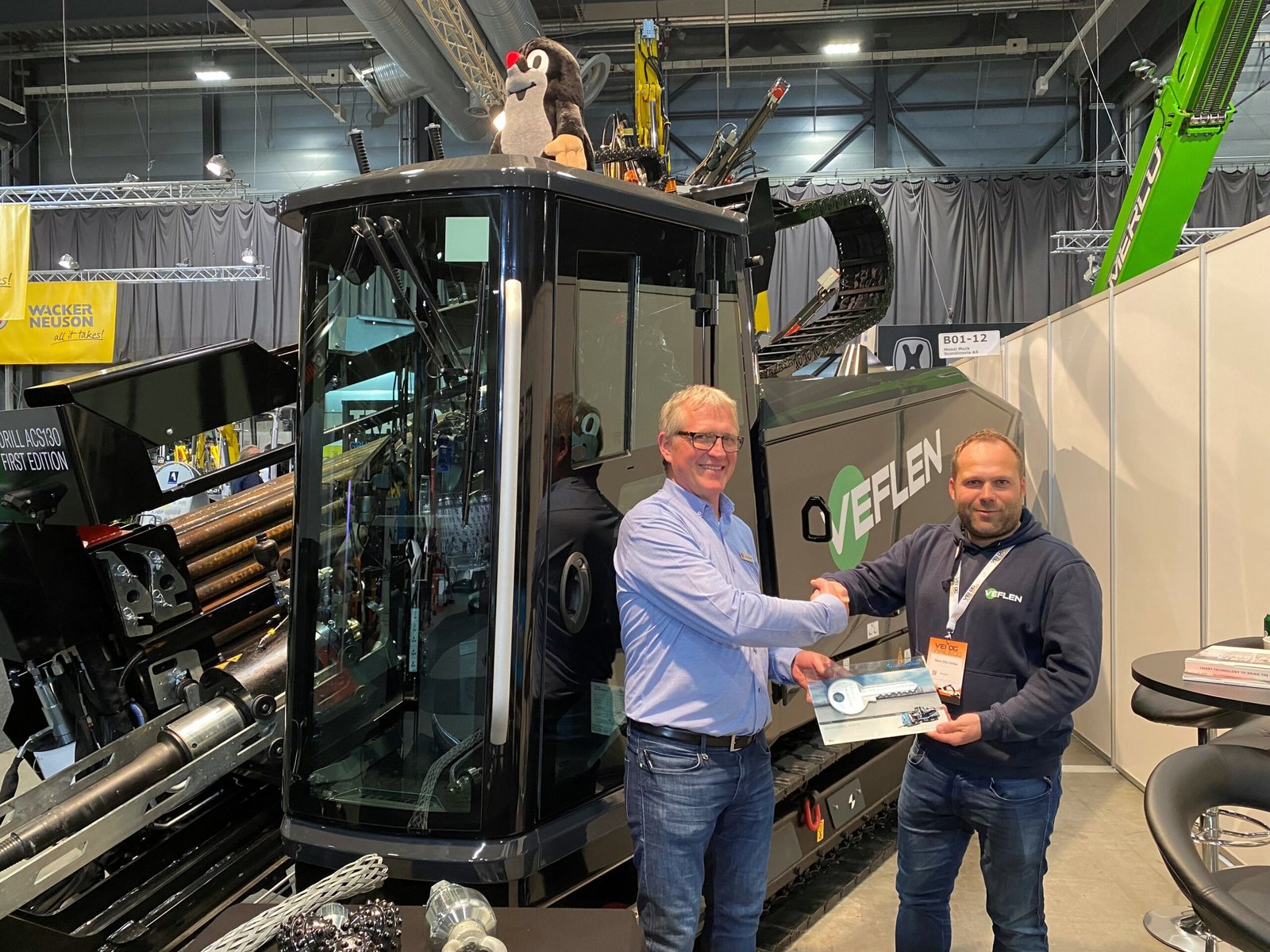 Bilde av to menn foran en maskin og de holder en stor nøkkel